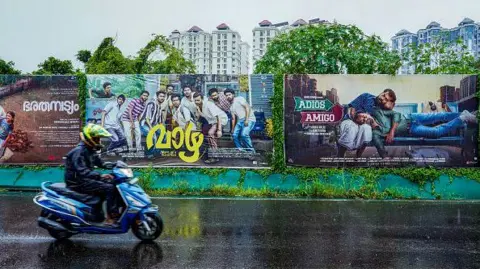 Getty Images Seorang pria membawa poster film daerah dari industri film Mollywood yang berbasis di Kerala di Kochi, India, pada 30 Agustus 2024, dipajang di jalan di tengah protes terhadap dugaan tuduhan seks dalam industri tersebut. 