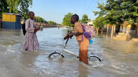     AHMED KINGIMI/Reuters Seorang pemuda Nigeria tenggelam di perairan dalam akibat banjir besar di Maiduguri, Nigeria - Selasa 17 September 2024.