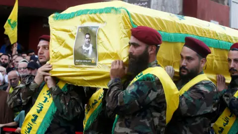 Reuters Anggota Hizbullah membawa peti mati Hassan Youssef Abdel Satter yang berbalut warna kuning, yang tewas dalam serangan Israel di pinggiran selatan Beirut pada hari Jumat.