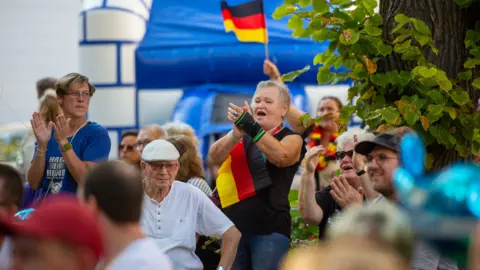 Getty Images Seorang wanita bersorak di rapat umum dengan bendera Jerman