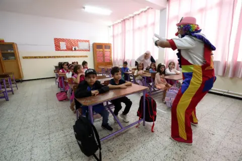 Billel Bensalem / AFP Seorang badut tampil di depan siswa di sebuah kelas di Aljazair pada 22 September 2024.