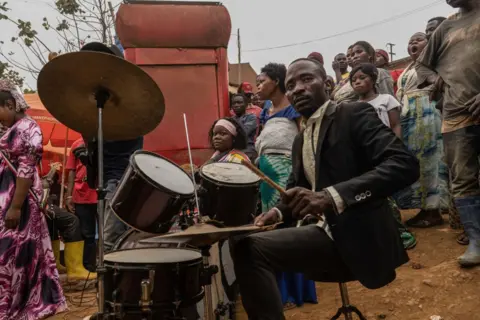 Glody Murhabazi / AFP Seorang pria memainkan drum saat kebaktian dadakan di jalan Kamituga, di Kivu Selatan, sebelah timur Republik Demokratik Kongo, pada 20 September 2024. 