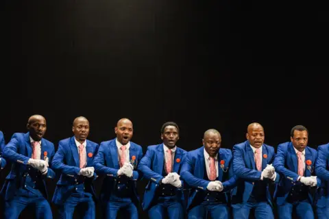 Rajesh Jantilal / AFP Kelompok tradisional Isikathamia menampilkan lagu dan tarian tradisional di atas panggung di Natal Playhouse Theatre di Durban pada 21 September 2024.