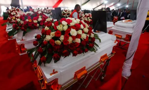     Monica Mwangi/Reuters Pekerja Palang Merah Kenya mengatur peti mati sebelum upacara peringatan di Kenya pada 26 September 2024.