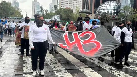 Para pengunjuk rasa memegang spanduk memperingati 43 siswa guru yang hilang di Mexico City