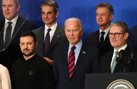 Getty Images Presiden AS Joe Biden (tengah), berdiri di samping Presiden Ukraina Volodymyr Zelensky (kiri) dan Perdana Menteri Inggris Keir Starmer (kanan), berkumpul untuk foto bersama di sebuah acara peluncuran pernyataan bersama dengan para pemimpin dunia untuk pemulihan Ukraina. Rekonstruksi dalam rangka Sidang Majelis Umum PBB ke-79 di New York pada 25 September 2024