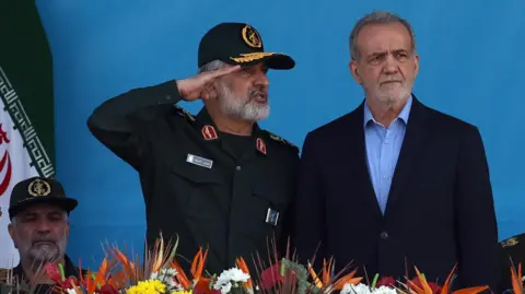 EPA Presiden Iran Masoud Pezheshkian (kanan) dan Komandan Pasukan Dirgantara Korps Pengawal Revolusi Islam, Amir Ali Hajizadeh (kiri), menghadiri parade militer di Teheran, Iran (21 September 2024).