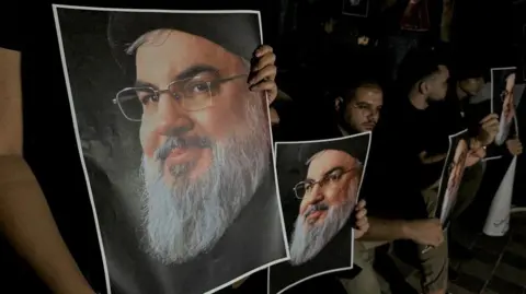 Reuters Para pendukung membawa foto pemimpin Hizbullah Lebanon Hassan Nasrallah saat ia berkumpul di Sidon, Lebanon setelah pembunuhannya.