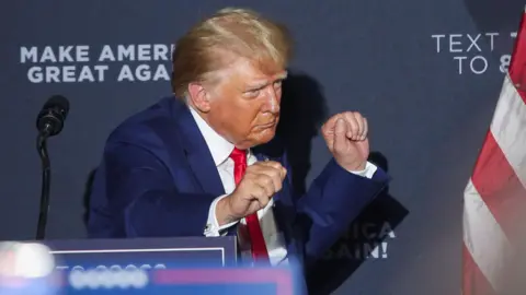 Reuters Donald Trump, mengenakan jas biru dan dasi merah, menari saat meninggalkan panggung pada kampanye di New Hampshire