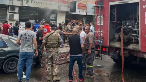 AFP Orang-orang dan petugas pertolongan pertama berkumpul di lokasi ledakan perangkat yang dilaporkan di Sidon, Lebanon selatan (18 September 2024)