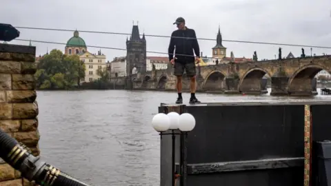     MARTIN DIVISEK/EPA-EFE/REX/Shutterstock Seorang pekerja bersiap menutup pintu air di Sungai Vltava di pusat kota Praha, Republik Ceko, 13 September 2024.