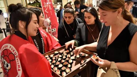 AFP Dua wanita berkimono Jepang memetik buah persik dari nampan yang mereka pegang