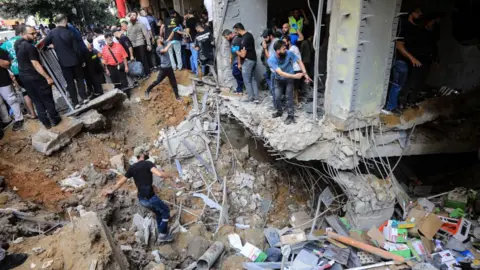 Getty Images Orang-orang memeriksa kerusakan akibat serangan Israel di pinggiran selatan Beirut pada 20 September 2024.