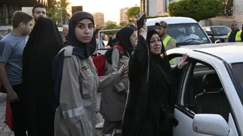 Seorang pekerja pertahanan sipil EPA menghibur seorang wanita yang meninggalkan Lebanon selatan di Beirut