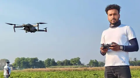 Vishal Jaiswal Vishal Jaiswal memegang pengontrol drone dan menerbangkan drone di dekatnya.