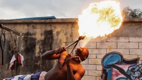     Emmanuel Adegboye / EPA Seorang pemadam api tampil saat pesta kumuh di Distrik Oworonshoki, Lagos, Nigeria pada 24 September 2024