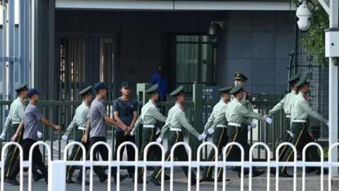 Getty Images Petugas polisi paramiliter Tiongkok berjalan melewati pintu masuk kedutaan Jepang di Beijing pada 19 September 2024.