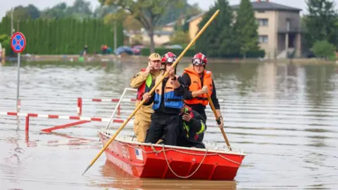 Tim penyelamat EPA menggunakan tiang untuk memindahkan rakit melintasi daerah banjir di Czekwis-Dzidzczyce, Polandia selatan