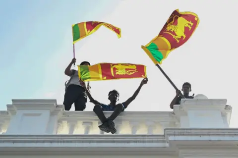 Getty Images Tiga pemuda melambai kepada fans Sri Lanka dari atas langkan beton putih