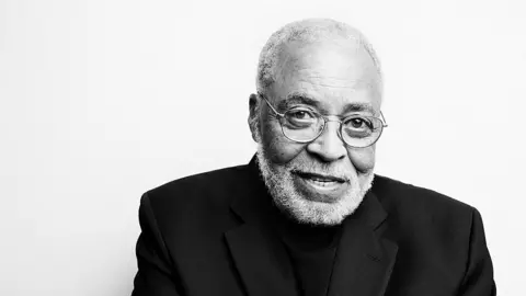 Getty Images Foto hitam putih James Earl Jones, berkacamata, jumper leher polo hitam, dan blazer hitam di atasnya.