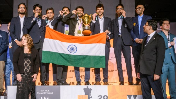 Tim India merayakan medali emas mereka dalam kategori terbuka di podium yang disaksikan oleh legenda catur Viswanathan Anand dan Susan Polgar. (FIDE/Michal Walusza)
