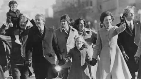 Getty Images Jimmy, Amy (tengah) dan Rosalyn Carter (kanan) berjalan di Parade Pelantikan Presiden tahun 1977 di Washington DC