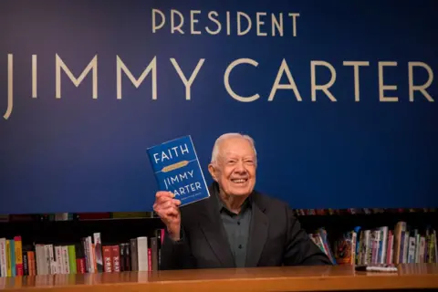 Getty Images Carter memegang salinan bukunya Faith: A Journey for All pada acara penandatanganan buku di New York pada tahun 2018