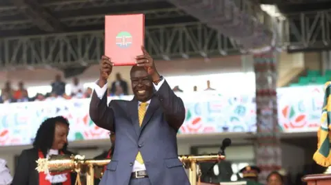 Getty Images Wakil Presiden Kenya Rigati Gachagua memegang sertifikat saat upacara pelantikan di Stadion Kasarani