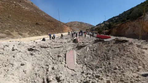 Kawah besar di tengah jalan dekat Persimpangan Masna pada 4 Oktober 2024 oleh Reuters