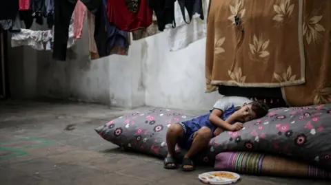 Reuters Seorang anak laki-laki pengungsi beristirahat di sebuah sekolah di Beirut yang menyediakan tempat penampungan sementara bagi keluarga. Dia memiliki sepiring makanan di kakinya saat dia bersandar ke satu sisi dengan kepala bertumpu pada bantal