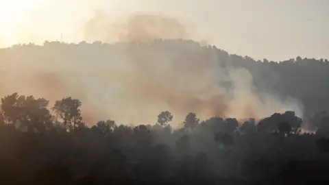 Reuters Asap mengepul dari perbukitan sekitar Kiryat Shmona di Israel utara setelah serangan roket Hizbullah (9 Oktober 2024).