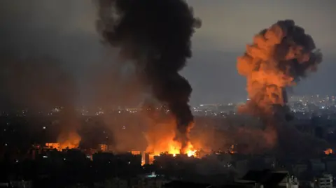 Asap EPA membubung akibat serangan udara Israel di kawasan Daheeh St. Therese di pinggiran selatan Beirut. Suar oranye juga terlihat di latar depan