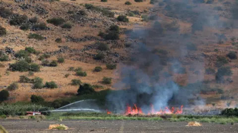 Petugas pemadam kebakaran EPA memadamkan api yang disebabkan oleh proyektil dari Lebanon selatan dekat Kfar Szold di Israel utara pada 11 Oktober 2024