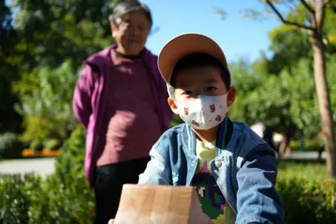 Seorang anak laki-laki memakai topeng di Ritan Park