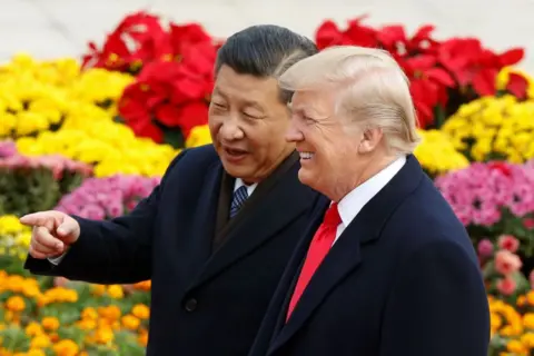 Getty Images Xi dan Trump di Beijing pada tahun 2017, berdiri di depan bunga