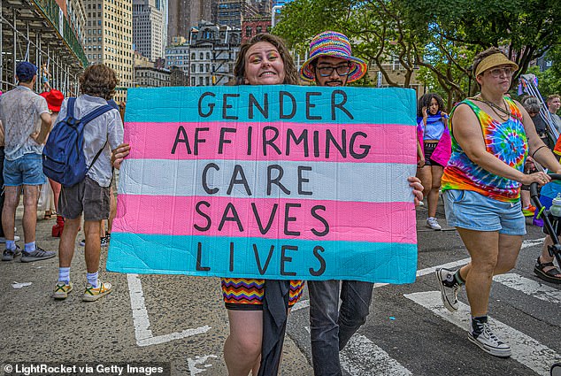 Seorang aktivis memegang papan yang dicat dengan warna-warna Trans Flag untuk mendukung kepedulian terhadap penegasan gender selama Queer Liberation March di New York City tahun lalu