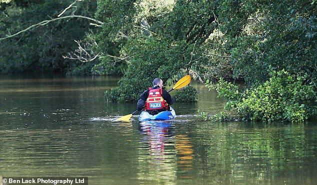 Seorang petugas polisi menggeledah tepi Sungai Derwent dengan kayak pada hari Jumat