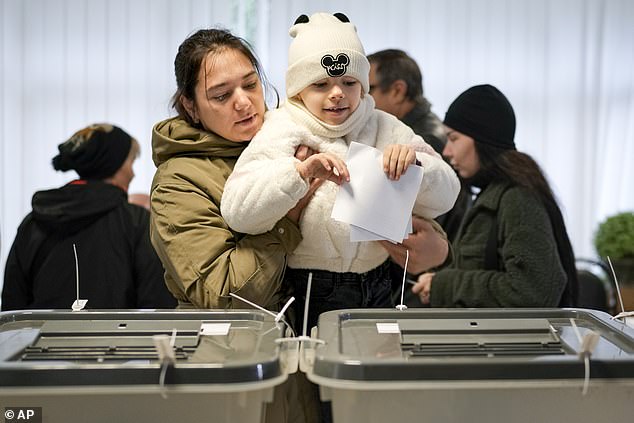 Seorang ibu menggendong seorang anak saat dia memberikan suaranya di Chisinau, Moldova, dalam pemilihan presiden dan referendum