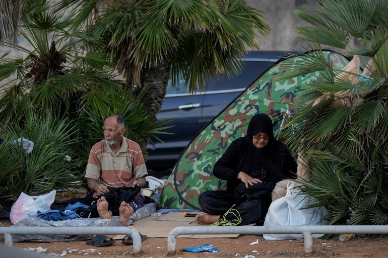 Sebuah keluarga pengungsi yang melarikan diri dari serangan udara Israel di selatan, duduk di trotoar di corniche Beirut, Lebanon, Senin, 14 Oktober