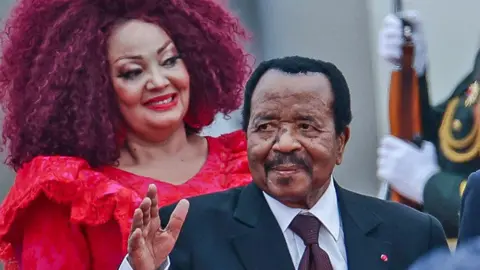 AFP Presiden Kamerun Paul Biya dihibur setibanya di Bandara Internasional Ibu Kota Beijing di Beijing, Tiongkok. Istrinya Chantal terlihat di belakangnya - 4 September 2024