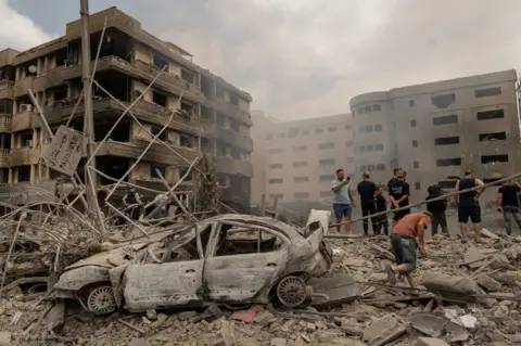 Joel Gunter/BBC Serangan udara Israel di lingkungan Daheeh menghancurkan klinik ginekologi Dr Tagrid Diab di gedung sebelah kiri gambar ini.