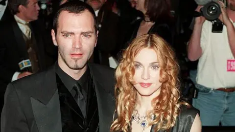 Getty Images Pasangan ini menghadiri beberapa acara bersama, termasuk pesta Oscar Vanity Fair tahun 1998. Ciccone mengenakan tuksedo hitam dan Madonna mengenakan gaun tanpa lengan berwarna hitam abu-abu dengan garis leher menjuntai.