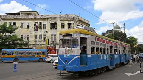 Dalam foto yang diambil AFP pada 8 September 2024 ini, penumpang sedang menaiki trem di sebuah jalan di Kolkata. Diperkenalkan di kota timur yang luas pada tahun 1873 pada masa awal Kerajaan Raj Inggris, trem Kolkata awalnya bertenaga kuda, kemudian bertenaga uap. Trem listrik mulai beroperasi pada tahun 1900. 