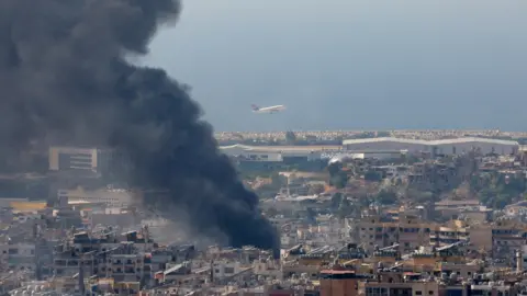 Reuters Sebuah pesawat lepas landas dari bandara Beirut saat asap mengepul dari pinggiran selatan kota menyusul serangan udara Israel (8 Oktober 2024).