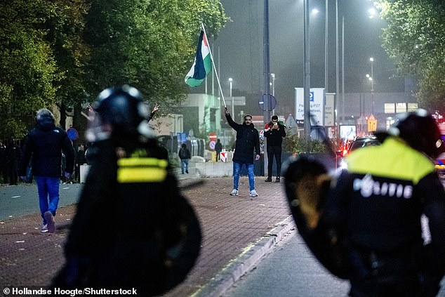 Seorang pengunjuk rasa dengan bendera Palestina dan Mobile Unit (ME) selama demonstrasi pro-Palestina selama Ajax - Maccabi Tel-Aviv di Anton de Komplein