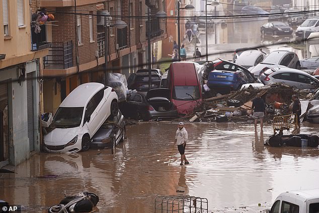 Warga melihat mobil-mobil menumpuk usai tersapu banjir