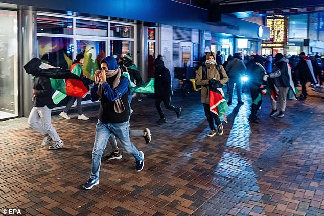 Kerumunan bertopeng, beberapa membawa bendera Palestina, terlihat melakukan kerusuhan di jalan-jalan Amsterdam pada hari Kamis.