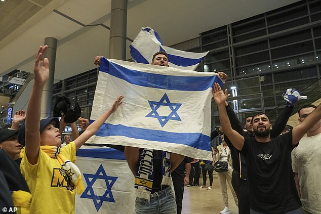 Orang-orang menyapa penggemar sepak bola Maccabi Tel Aviv saat mereka tiba di Bandara Internasional Ben-Gurion Israel dalam penerbangan dari Amsterdam