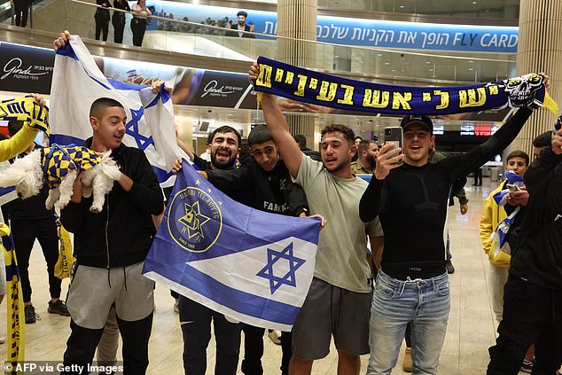 Penggemar Maccabi Tel-Aviv membawa bendera menunggu kedatangan teman dan keluarga dari Amsterdam di Bandara Internasional Ben Gurion