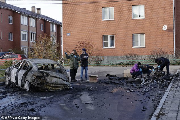 Petugas polisi Rusia memeriksa puing-puing drone di dekat mobil yang terbakar di halaman bangunan tempat tinggal setelah serangan drone di desa Sofyino, wilayah Moskow, pada 10 November.